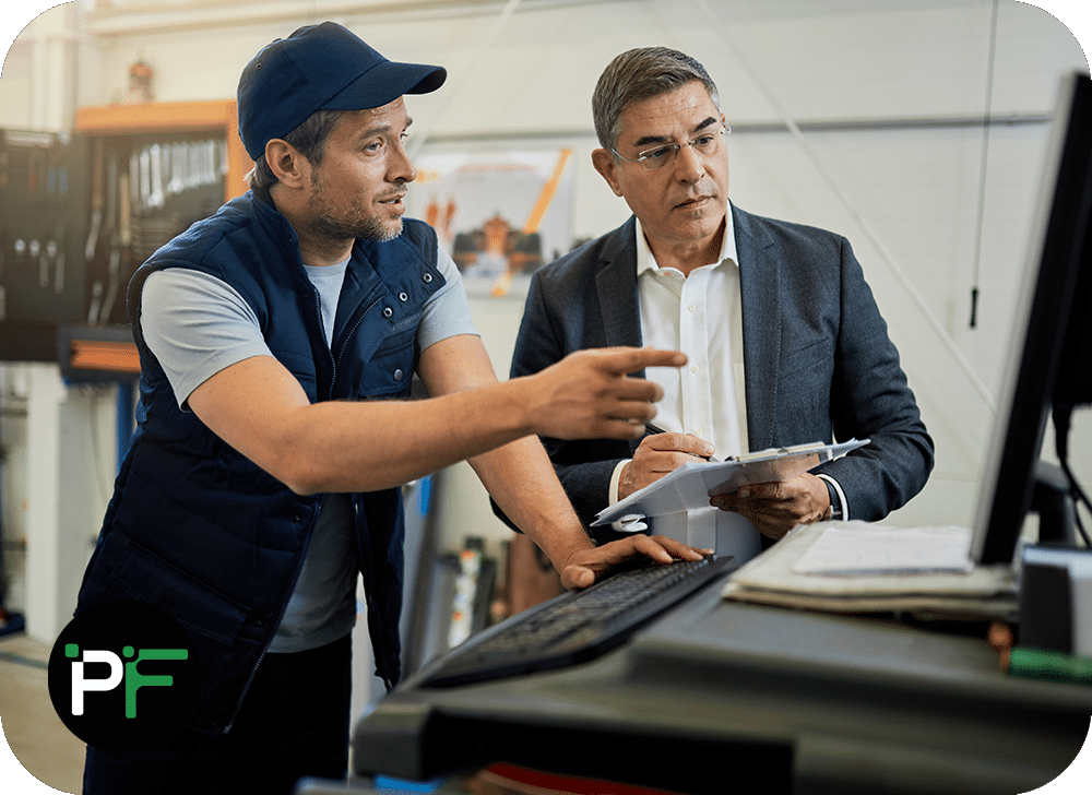 Two men pointing at a computer screen discussing requirements for CRM software development
